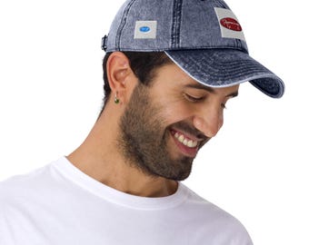 May include: A denim baseball cap with a curved brim and adjustable strap. The cap features two patches: one with a blue oval and another with red text on a white oval. The cap is a faded blue color.