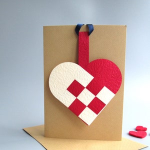 Scandinavisch geweven hart kerstwenskaart met afneembare hangende decoratie.