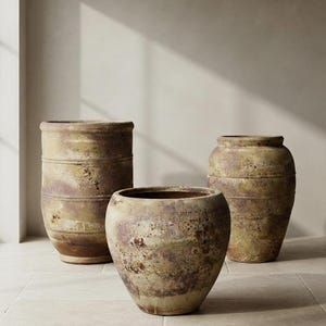 Puede incluir: Tres grandes recipientes de cerámica desgastada con un acabado terroso y moteado en tonos verde oliva, marrón y ocre. Las macetas presentan una silueta redondeada y bulbosa con crestas horizontales y una superficie texturizada.