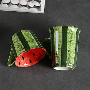 Op de afbeelding: Een set van drie keramische mokken met een gespikkelde, matte afwerking. De mokken zijn in de tinten crème, lichtgrijs en donkergrijs. Elke mok heeft een eenvoudig, minimalistisch ontwerp en een afgeronde handgreep.