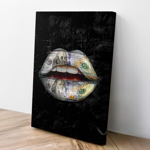 Puede incluir: Impresi&oacute;n en lienzo que representa unos labios hechos con billetes de cien d&oacute;lares. Los labios est&aacute;n sobre un fondo negro texturizado. La obra de arte est&aacute; apoyada contra una pared blanca y una superficie de madera.