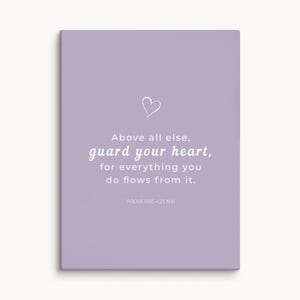May include: A rectangular canvas print with a light purple background. The print features a white heart graphic and text that reads "Above all else, guard your heart, for everything you do flows from it. PROVERBS 4:23 NIV."