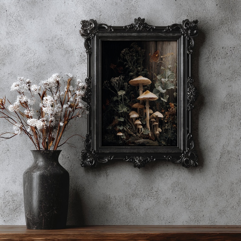 Peut inclure: Une impression d'art encadr&eacute;e en noir repr&eacute;sentant des champignons. L'&oelig;uvre d'art est plac&eacute;e sur un fond sombre avec un panneau de bois et du feuillage. Un vase noir avec des fleurs blanches se trouve &agrave; gauche de l'&oelig;uvre encadr&eacute;e.