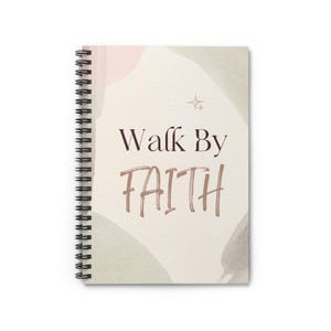 May include: A cream-coloured spiral-bound notebook featuring the words "Walk By FAITH" in brown script. The cover has abstract pink and grey watercolour shapes. A small star graphic is above the word "FAITH".