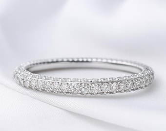 May include: A silver-toned eternity band ring featuring a continuous row of small, round, clear faceted stones set along the entire outer circumference of the metal band, creating a uniform, sparkling appearance across the surface of the jewellery.