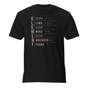 May include: A black short-sleeve t-shirt featuring a graphic print of the word ELEMENT spelled vertically in gray. Beside each letter is the corresponding NATO phonetic alphabet word and Morse code symbol in blue, tan, red, and white.