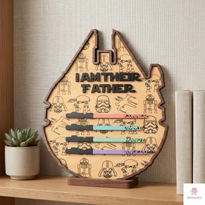 a wooden trophy or award shaped like the Millennium Falcon from the Star Wars franchise, with the text "I AM THEIR FATHER" and various Star Wars characters and symbols printed on it.