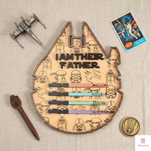 a wooden board with a Star Wars theme, including various characters and a message that reads "I am their father". There are also some Star Wars-themed items, such as a toy spaceship and a Star Wars poster, as well as a small wooden pen and a small Star Wars charm.