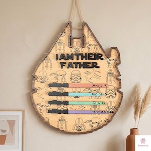 a wooden sign with a Star Wars theme, hanging on a wall. The sign has a Star Wars logo and various Star Wars characters printed on it.