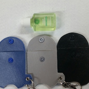 May include: Three different colored leather keychains with snap closures and a metal ring. The keychains are designed to hold a small bottle of hand sanitizer. The keychains are blue, gray, and black.
