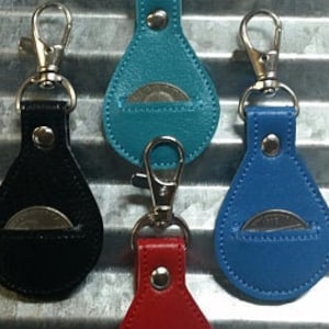May include: Four leather coin pouches with a snap closure and a key ring. The pouches are in black, teal, blue, and red.