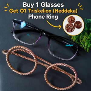 May include: Black-framed glasses with a gradient tint and a copper-colored twisted metal frame accessory. Text reads: Buy 1 Glasses Get 01 Triskelion (Heddeka) Phone Ring. A circular inset shows three copper spiral phone rings.