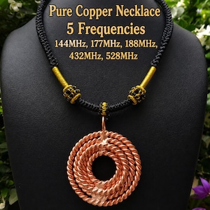May include: A necklace featuring a circular pendant made of twisted copper wire. The pendant hangs from a black braided cord accented with gold-colored thread. Text on the image reads: Pure Copper Necklace 5 Frequencies 144MHz, 177MHz, 188MHz, 432MHz, 528MHz.