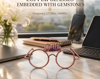 Op de afbeelding: Koperen bril met een gedraaid draadframe en een paarse edelsteen ingebed in de brug. De tekst COPPER GLASSES EMBEDDED WITH GEMSTONES en Frequency 177Mhz, 144Mhz is zichtbaar boven dit decoratieve object.