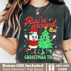 Może przedstawiać: Ciemnoszara koszulka z grafiką o tematyce świątecznej. Projekt przedstawia kreskówkową fiolkę Rocuronium i choinkę z napisem "Roc'n around the Christmas tree". Projekt zawiera płatki śniegu i gwiazdki.