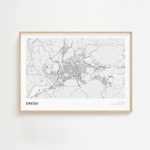 May include: A framed black and white map of Daegu, South Korea. The map shows the city's layout with roads and buildings. The word "DAEGU" is printed in a bold, sans-serif font at the bottom left.