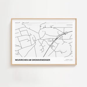 May include: A framed black and white map print of Neukirchen am Großvenediger, Austria. The map features a detailed street layout with the town's name at the bottom. The print is in a light wood frame.