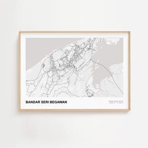 May include: A framed map print of Bandar Seri Begawan, Brunei, in shades of grey. The map shows the city's road network and surrounding areas in detail. The print is in a light-coloured wooden frame.