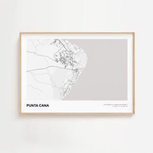 May include: A framed print featuring a minimalist map of Punta Cana, Dominican Republic. The map is in grayscale, with the city and roads depicted in white against a light gray background. The text "PUNTA CANA" is at the bottom.