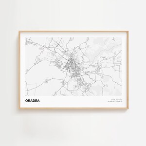 Op de afbeelding: Een zwart-wit kaart van Oradea, Roemenië, in een lijst. De kaart toont het wegennetwerk van de stad en de omliggende gebieden. De naam van de stad staat vetgedrukt linksonder. De lijst is licht van kleur.