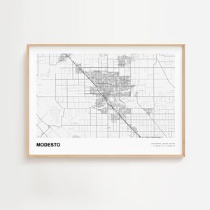 May include: A framed black and white map print of Modesto, California, with the city's name at the bottom. The map shows roads and buildings in detail. The frame is a light wood color.