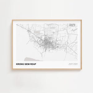 Pode incluir: Um mapa a preto e branco emoldurado de Krong Siem Reap, Camboja. O mapa detalha a rede rodoviária e o layout urbano da cidade. O texto "KRONG SIEM REAP" é impresso na parte inferior esquerda, com coordenadas na parte inferior direita.