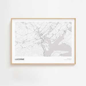 May include: A framed print featuring a detailed map of Lucerne, Switzerland, in grayscale. The map shows the city's layout with roads and waterways. The word "LUCERNE" is printed in bold, with "SWITZERLAND" and coordinates below.