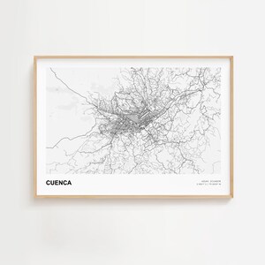 May include: A framed black and white map print of Cuenca, Ecuador. The map shows the city's layout with roads and buildings. The print includes the city name at the bottom left and coordinates at the bottom right.