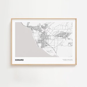Może przedstawiać: Oprawiony czarno-biały wydruk mapy Oxnard w Kalifornii, z nazwą miasta pogrubioną u dołu. Mapa przedstawia drogi i cechy geograficzne. Rama jest w jasnym kolorze drewna.