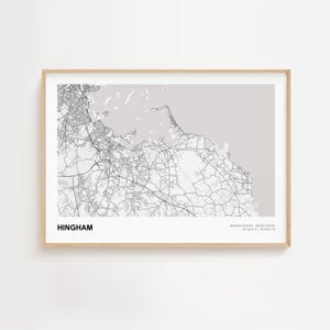 May include: Framed map print of Hingham, Massachusetts, in black and white. The map shows the town's roads and waterways. The town's name is printed in a bold font at the bottom left. The frame is a light wood color.