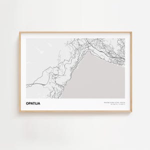 Op de afbeelding: Een ingelijste kaartafdruk van Opatija, Kroatië, in zwart-wit. De kaart toont een gedetailleerde lijntekening van de stadsindeling, met de stadsnaam linksonder en de coördinaten rechtsonder.
