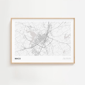 May include: A framed monochrome map print of Waco, Texas, showing the city's layout and surrounding roads. The word "WACO" is printed at the bottom left. The frame is a light wood colour. The map includes the coordinates.