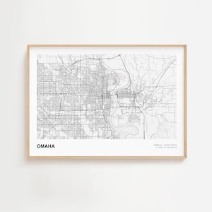 Puede incluir: Un mapa en blanco y negro enmarcado de Omaha, Nebraska, con la red de carreteras de la ciudad y los alrededores. La palabra "OMAHA" está impresa en negrita en la parte inferior izquierda. El marco es de color madera clara.