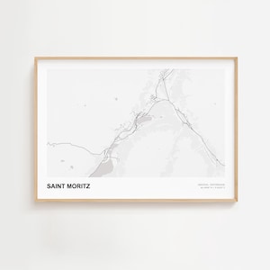 May include: A framed print featuring a grayscale map of Saint Moritz, Switzerland. The map details the topography and road network of the area. The text "SAINT MORITZ" is at the bottom left, with coordinates at the bottom right.