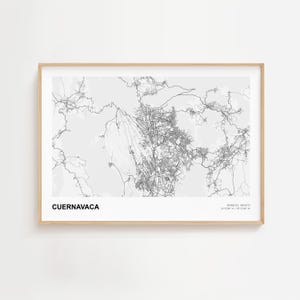 May include: A framed grayscale map print of Cuernavaca, Mexico. The map shows detailed street and terrain outlines. The print is in a light wood frame and includes the city name and coordinates.