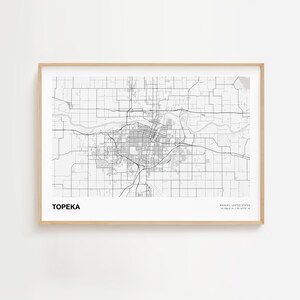 Może przedstawiać: Oprawiona czarno-biała mapa Topeka, Kansas, z nazwą miasta wydrukowaną w lewym dolnym rogu. Mapa przedstawia układ miasta, ulice i okolice. Rama ma jasny kolor drewna.