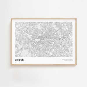 May include: A framed monochrome map of London, England, showing the city's road network and the River Thames. The word "LONDON" is printed in bold black text at the bottom left. The frame is a light wood color.