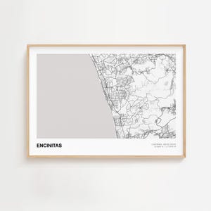 May include: A framed map print of Encinitas, California, in monochrome. The map details the city's layout with roads and geographical features. The text "ENCINITAS" is at the bottom, with coordinates and "CALIFORNIA, UNITED STATES" below it.