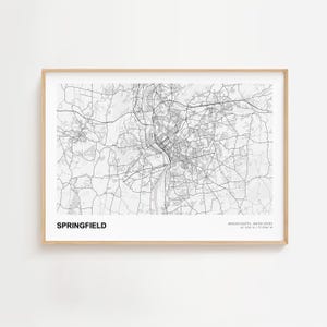 Puede incluir: Una impresión enmarcada en blanco y negro de un mapa de Springfield, Massachusetts, Estados Unidos. El mapa muestra la red de carreteras y las características geográficas de la ciudad. La palabra "SPRINGFIELD" está impresa en negrita negra en la parte inferior.