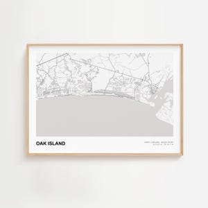 May include: A framed map print of Oak Island, North Carolina, in grayscale. The map shows the coastal area with roads and geographical features. The text "OAK ISLAND" is at the bottom, with coordinates and "NORTH CAROLINA, UNITED STATES" below it.