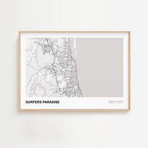 May include: A framed map print of Surfers Paradise, Australia. The black and white map details the city's layout, including roads and waterways. The text "SURFERS PARADISE" is at the bottom left, with coordinates on the right.