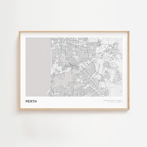 Puede incluir: Una impresión enmarcada en blanco y negro del mapa de Perth, Australia Occidental. El mapa detallado de la ciudad muestra calles y vías fluviales. La palabra "PERTH" está impresa en la parte inferior izquierda. El marco es de color madera clara.