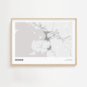May include: A framed print featuring a detailed grayscale map of Fethiye, Turkey. The map highlights the city's roads and geographical features. The word "FETHIYE" is printed in bold, centered at the bottom, with coordinates and the region name in the bottom right corner.