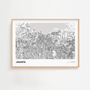 Op de afbeelding: Een ingelijste kaartprint van Jakarta, Indonesië, in grijstinten. Het gedetailleerde wegennetwerk van de stad en de omgeving zijn zichtbaar. Het woord "JAKARTA" is vetgedrukt, met coördinaten eronder.