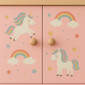 May include: A pink cabinet with a light wood top and wooden knobs. The cabinet doors feature illustrations of unicorns, rainbows, stars, and clouds in pastel colours. The cabinet is designed for children's rooms.