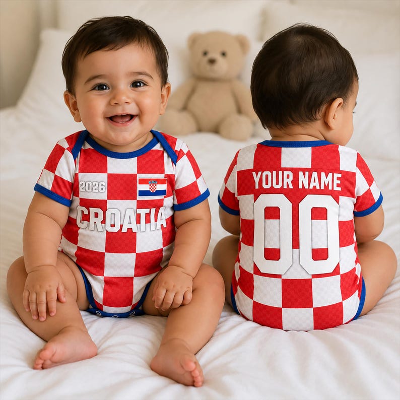 K&ouml;nnte beinhalten: Ein rot-wei&szlig; karierter Babybody mit blauen R&auml;ndern. Die Vorderseite zeigt den Text 2026, das Wort CROATIA und eine kleine kroatische Flagge. Die R&uuml;ckseite zeigt den Text YOUR NAME &uuml;ber der Nummer 00 in gro&szlig;er wei&szlig;er Schrift mit blauem Rand.
