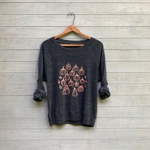 May include: A dark gray sweatshirt with a pink pumpkin design. The pumpkins are of various sizes and shapes.