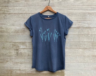 May include: A dark blue t-shirt with a light blue floral design on the front. The shirt has rolled up sleeves and a crew neck.