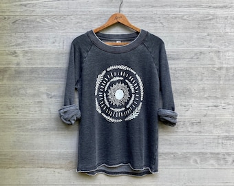 May include: A dark gray sweatshirt with a white graphic of a sun with a mandala design surrounded by leaves.