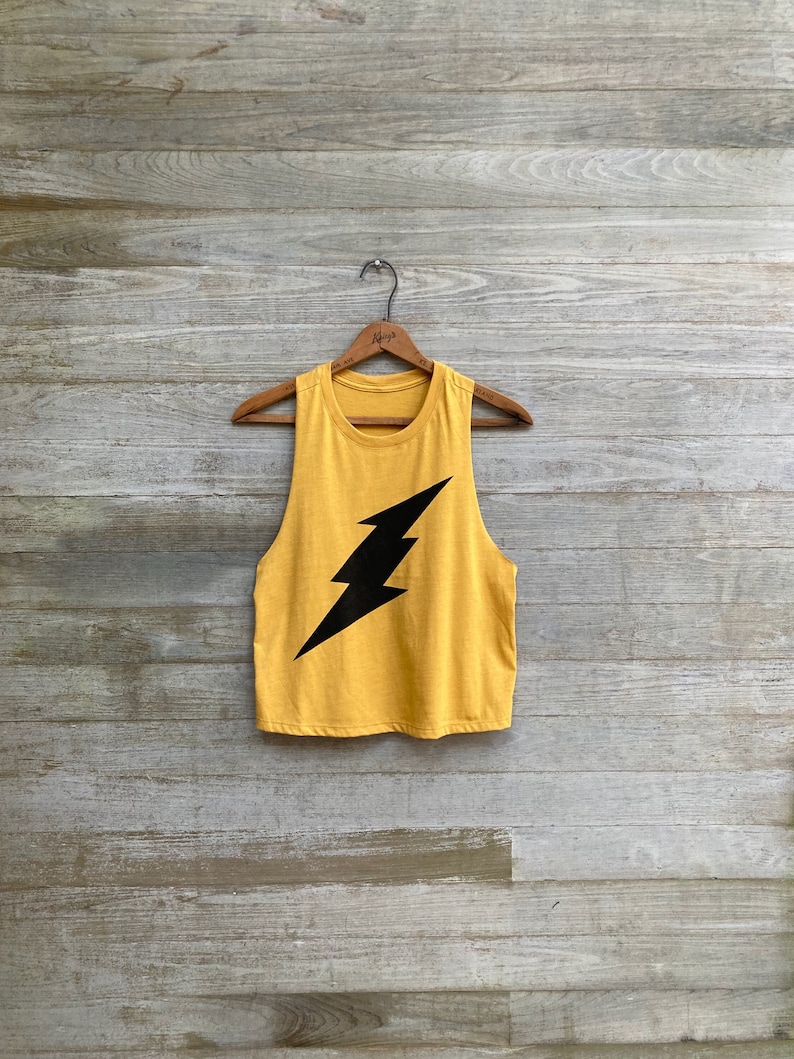 May include: A mustard yellow sleeveless tank top with a black lightning bolt graphic.
